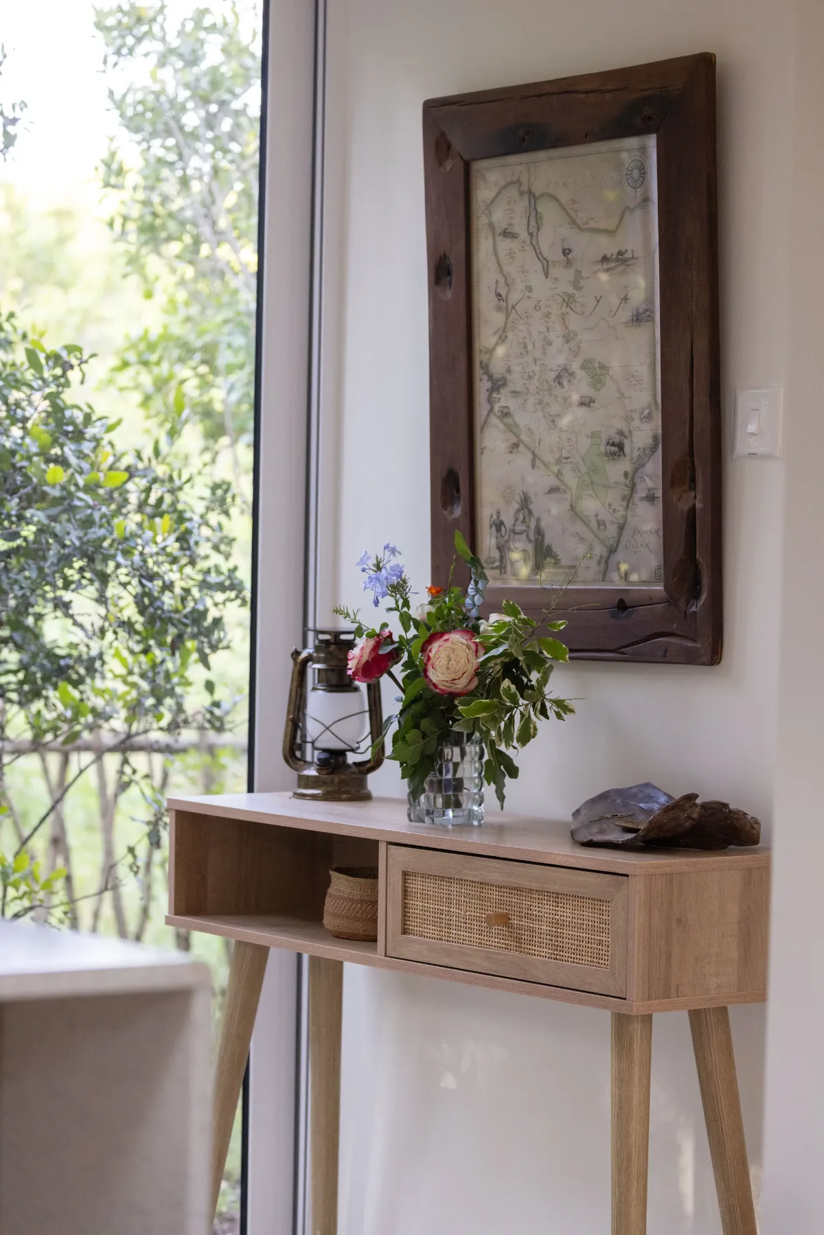 A console table with an old map of Kenya, lantern and garden flowers