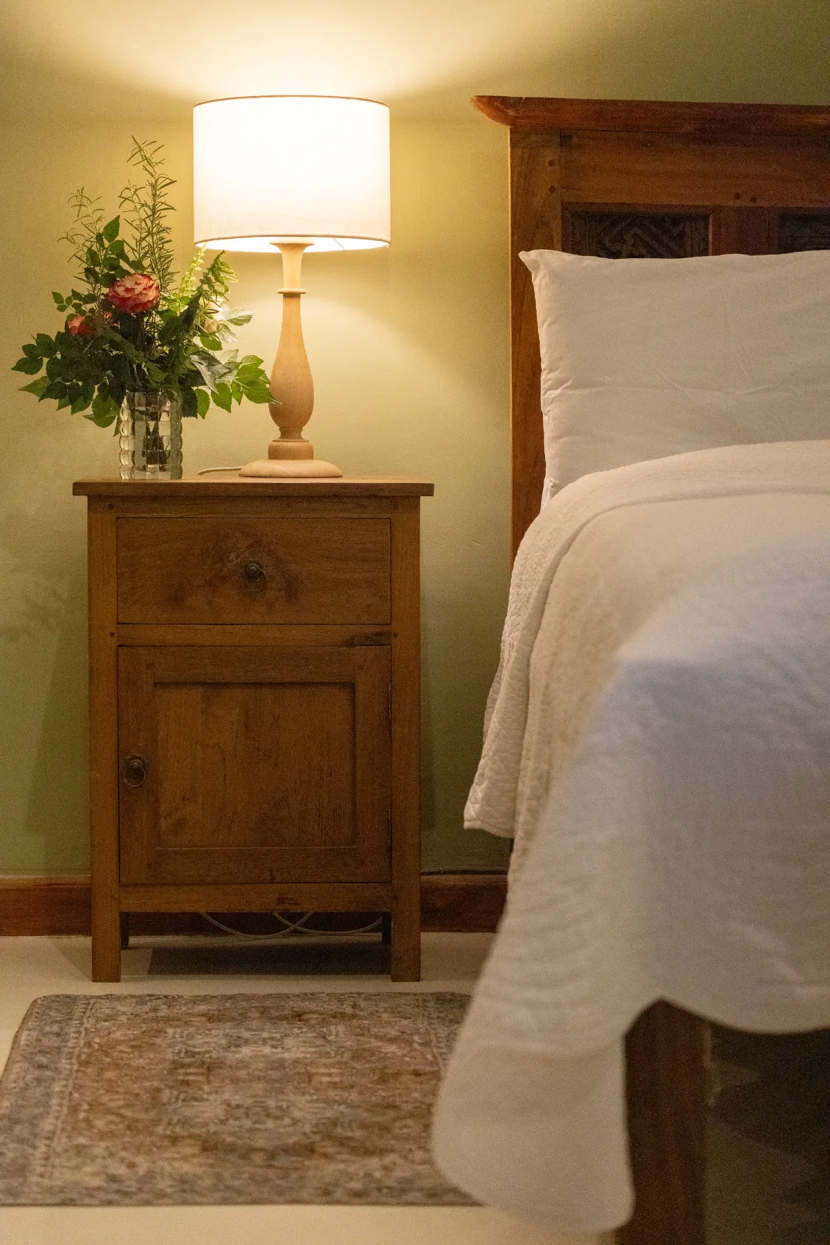 Bedside lamp and garden flowers beside the bed in Wild Poetry